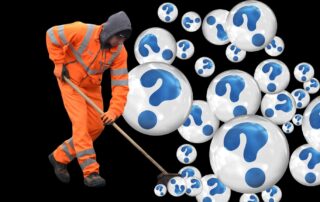 Ein Arbeiter in orangener Uniform kehr mit einem Besen weiße Bälle mit blauen Fragezeichen darin