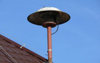 Feuermelder auf einem Dach vor blauem Himmel