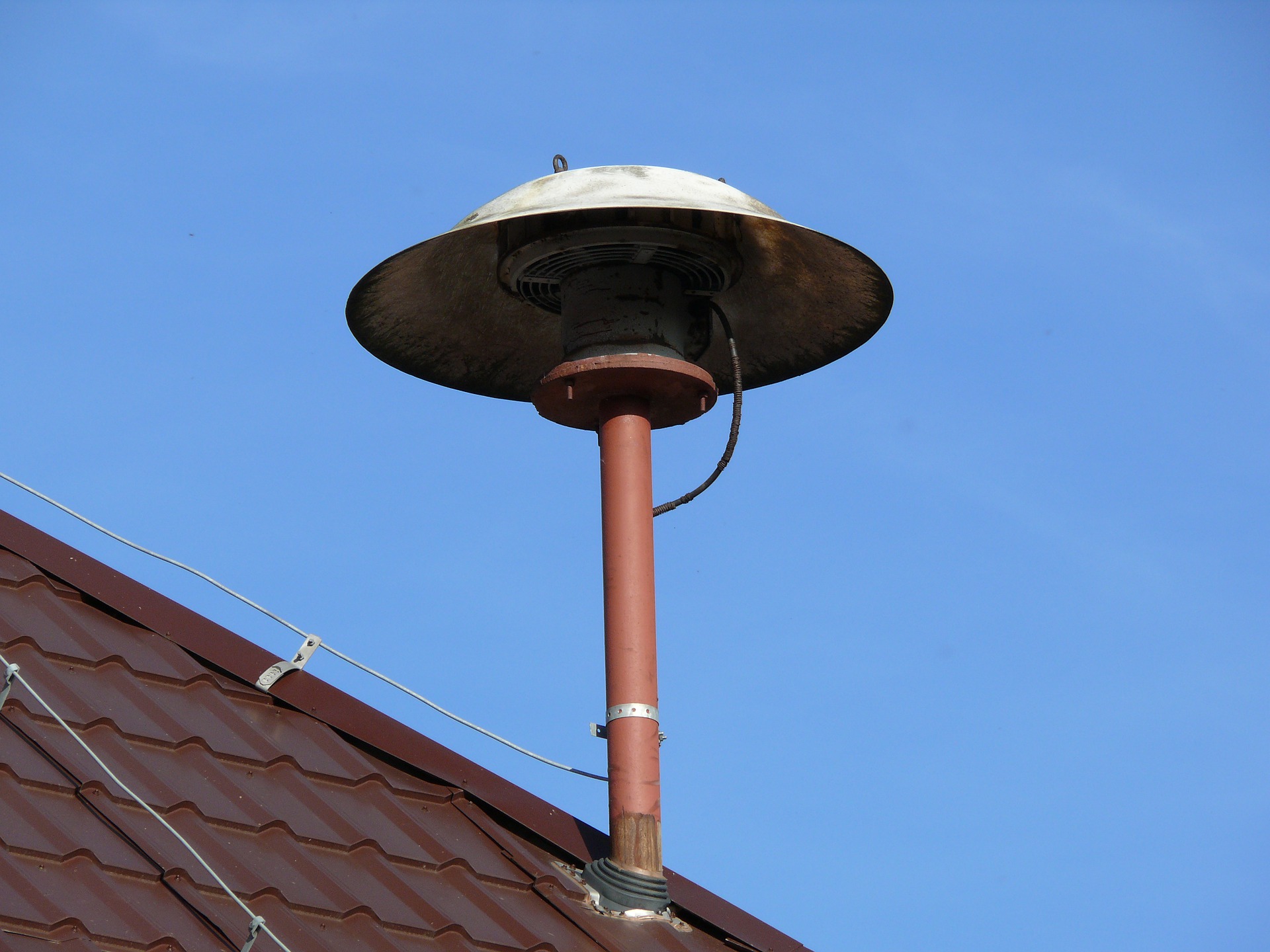 Feuermelder auf einem Dach vor blauem Himmel