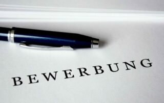Weißes Blatt mit einem Stift und darauf steht das Wort Bewerbung