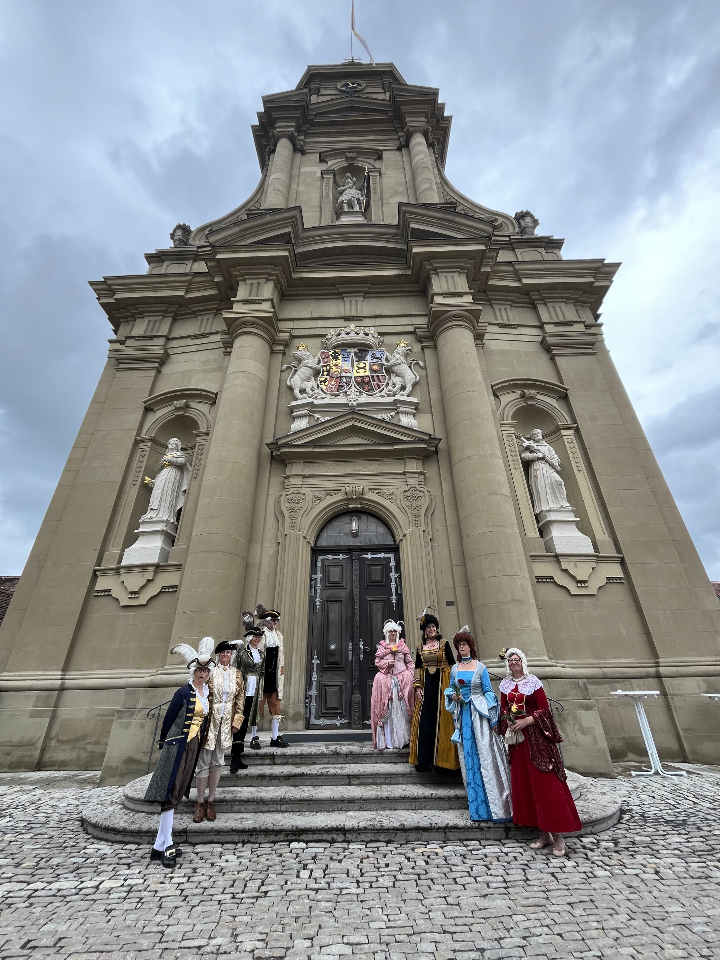 Mauritiuskirche in Wiesentheid mit den Barockdamen und -herren im Vordergrund in barocken Gewändern
